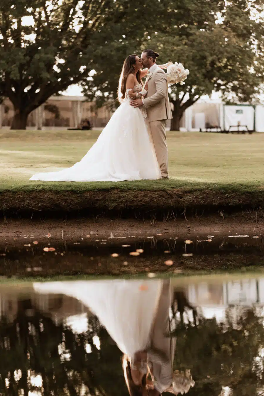 Bride and Groom by Lake with marquee in background at That Amazing Place Essex Wedding Venue