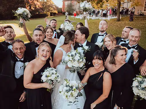 Bride and groom kissing surrounded by bridal party at That Amazing Place Essex Wedding Venue
