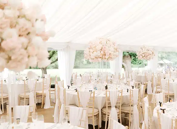 Marquee wedding set up with pink and white flowers and chair sashes at That Amazing Place Essex Wedding Venue View