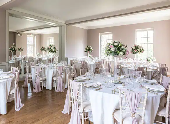Marquee wedding set up with green and white flowers and chair sashes at That Amazing Place Essex Wedding Venue